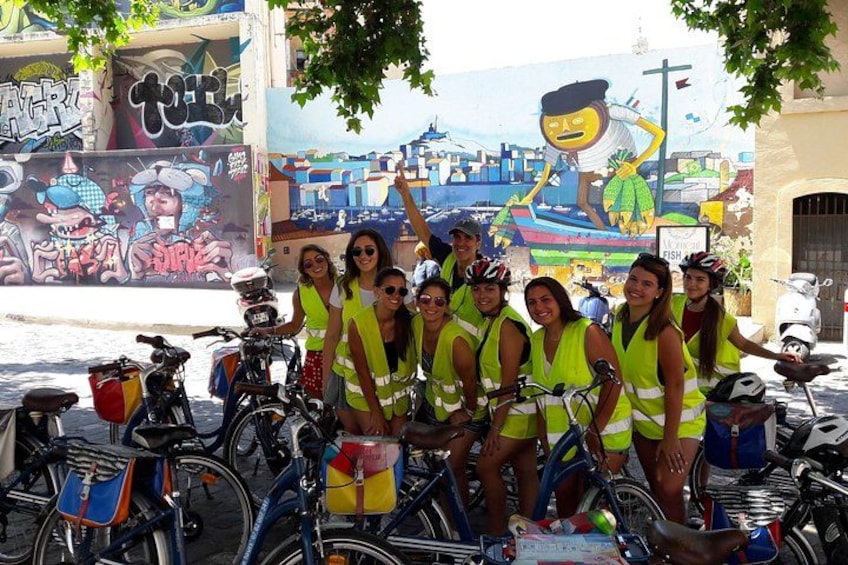 A group of people on bicycles with a mural in the background. 5