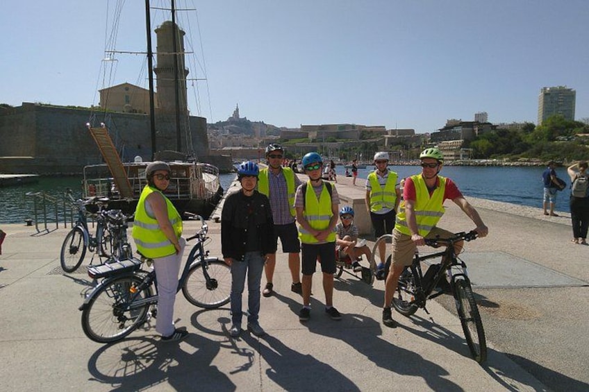 A group of people with bicycles near a waterfront, wearing safety vests. 2