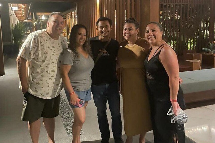 A group of people standing indoors with wooden paneling and a bench in the background. 4