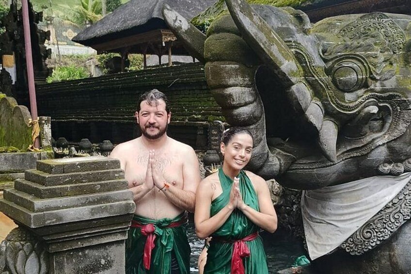 A man and a woman in traditional attire standing in front of a stone structure with a large carved face. 2