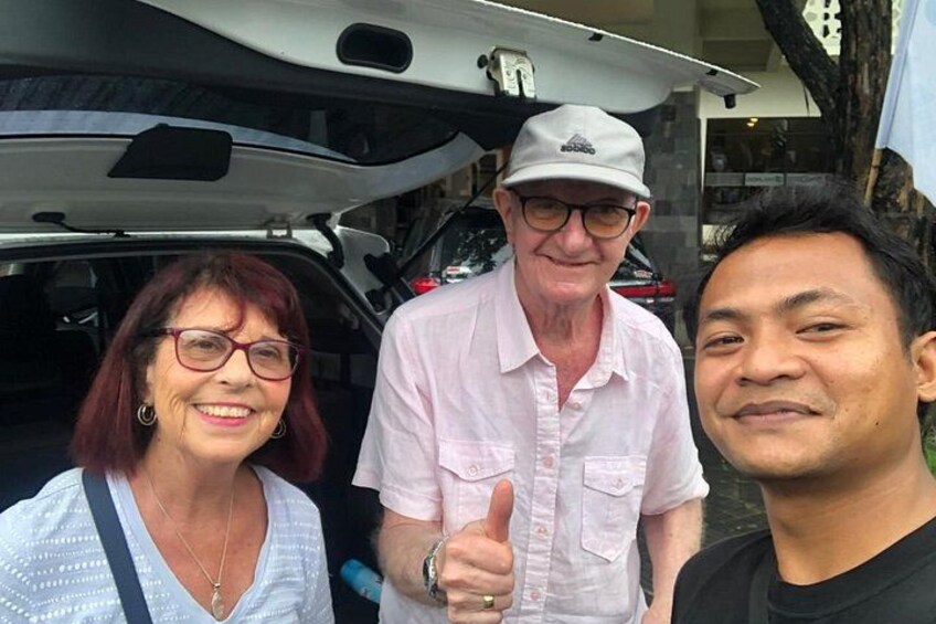 Three people standing in front of a vehicle with an open trunk. 3