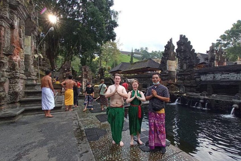 A temple with stone carvings, a water feature, and people in traditional attire. 5