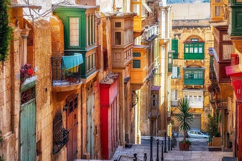 A narrow street with colorful buildings, a palm tree, and a parked car. 2