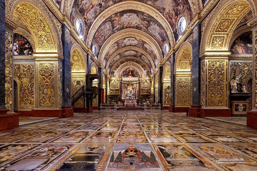 An ornate church interior with detailed frescoes, a central altar, and a tiled floor. 5
