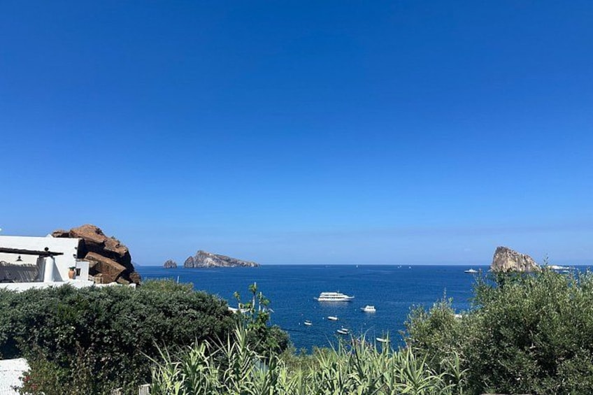 Un paysage côtier caractérisé par des affleurements rocheux, un ciel bleu dégagé et quelques bateaux sur l’eau. 4