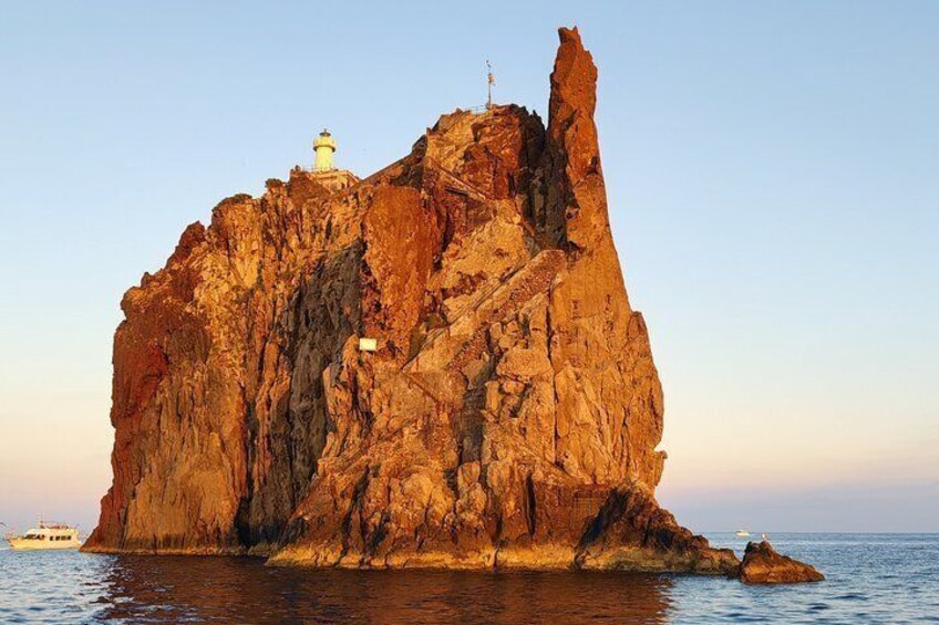 A rocky island with a lighthouse and a boat in the water. 2