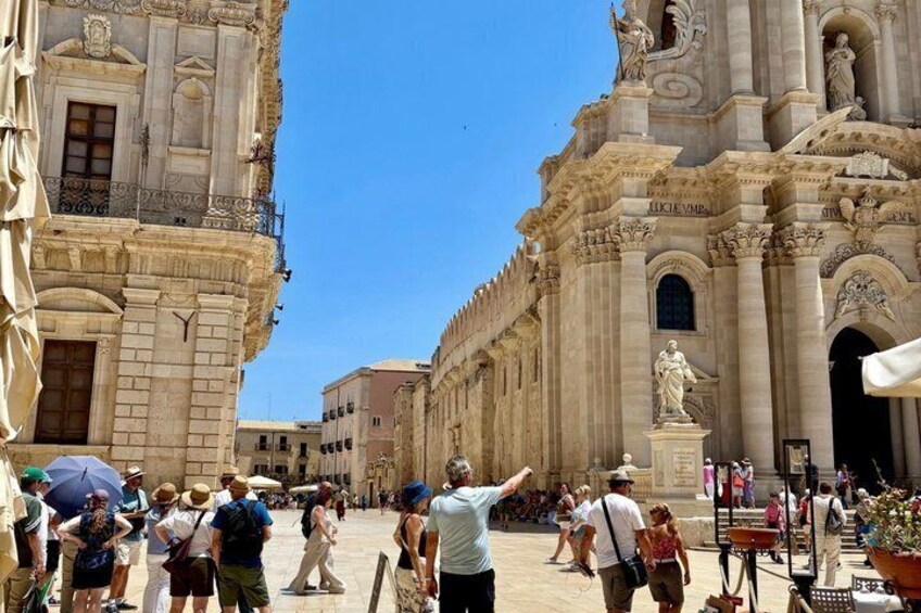 A historic plaza with tourists, a prominent cathedral, and classical architecture. 4
