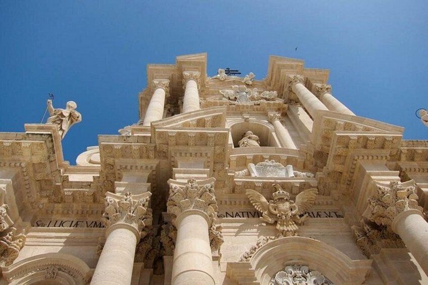 Une façade architecturale richement détaillée, ornée de colonnes, de statues et d’inscriptions. 4