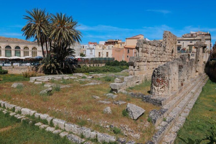 Ruines antiques, avec des palmiers et des bâtiments modernes en arrière-plan. 4