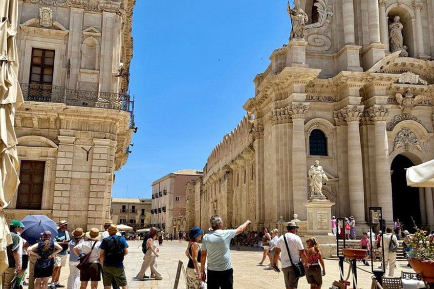 Une place historique, fréquentée par des touristes, avec un grand bâtiment orné et une statue. 3