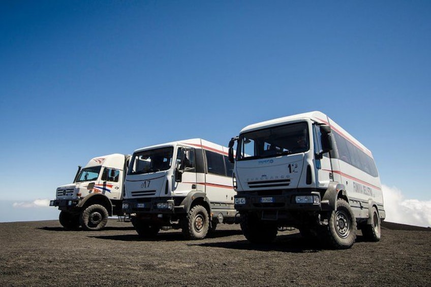 Tres camiones blancos con franjas rojas estacionados sobre una superficie plana bajo un cielo despejado. 4