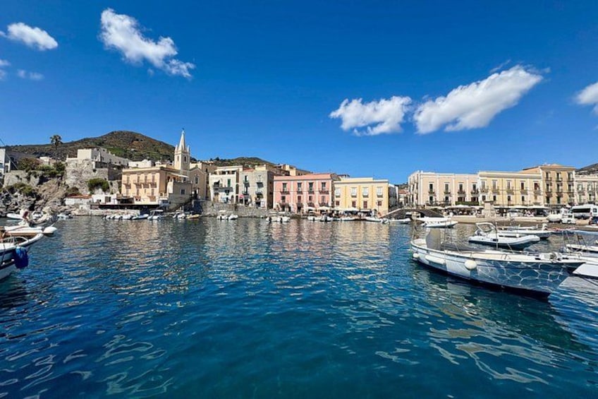 A coastal town with a clear blue sea, boats docked along the waterfront, and colorful buildings. 4