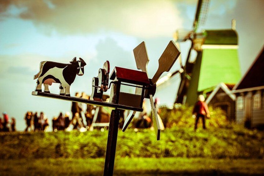 Un moulin à vent surmonté d’une figurine de vache, une éolienne et, au fond, un bâtiment doté d’un toit végétalisé. 3