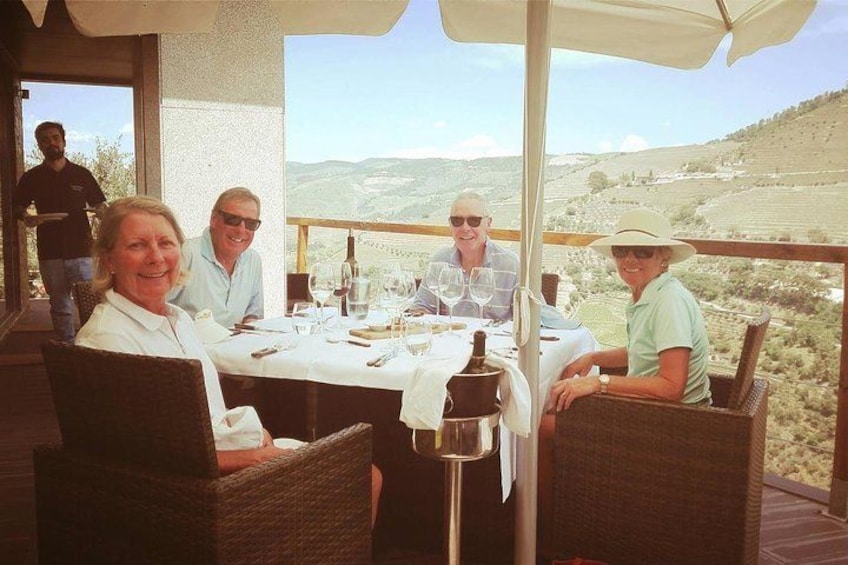 A group of people dining at an outdoor table with a scenic view. 3