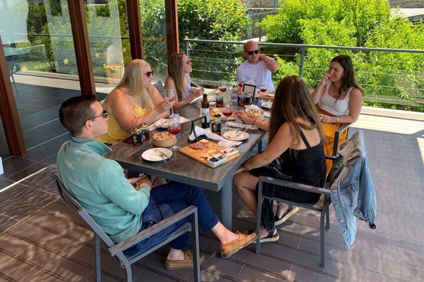 A group of people dining at an outdoor table with a view of greenery. 5
