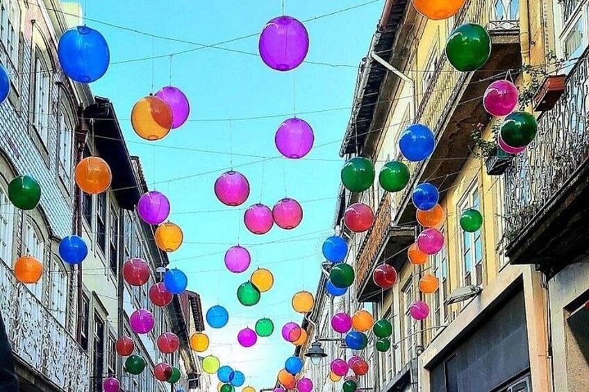A street with colorful spherical decorations hanging between buildings. 3