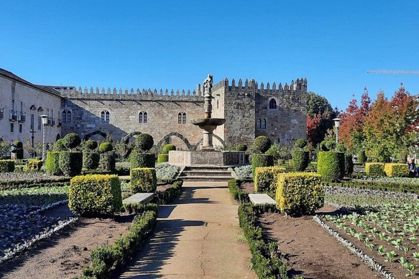 A castle with a well-manicured garden, a fountain, and a clear blue sky. 5