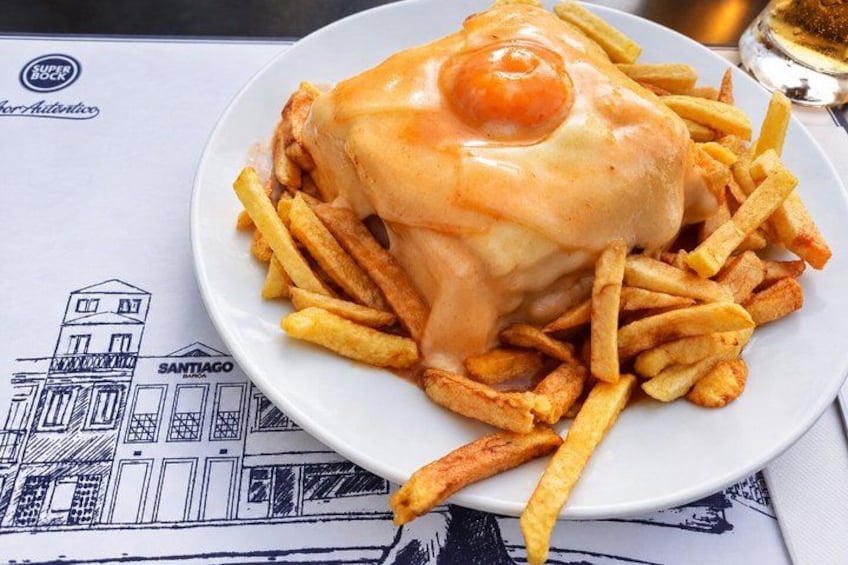 A plate of French fries topped with a fried egg and cheese, with a building illustration on the tablecloth. 2