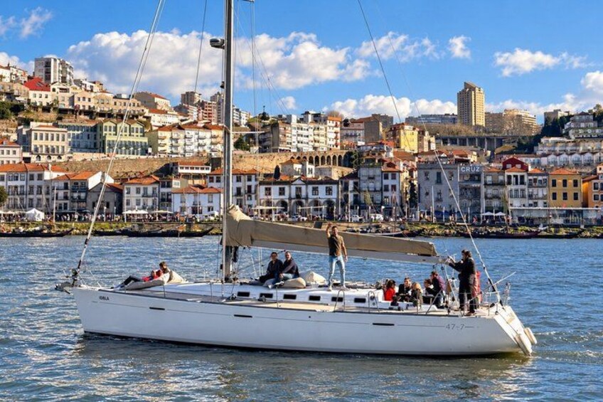 A sailboat with people on board, docked near a city with colorful buildings. 4