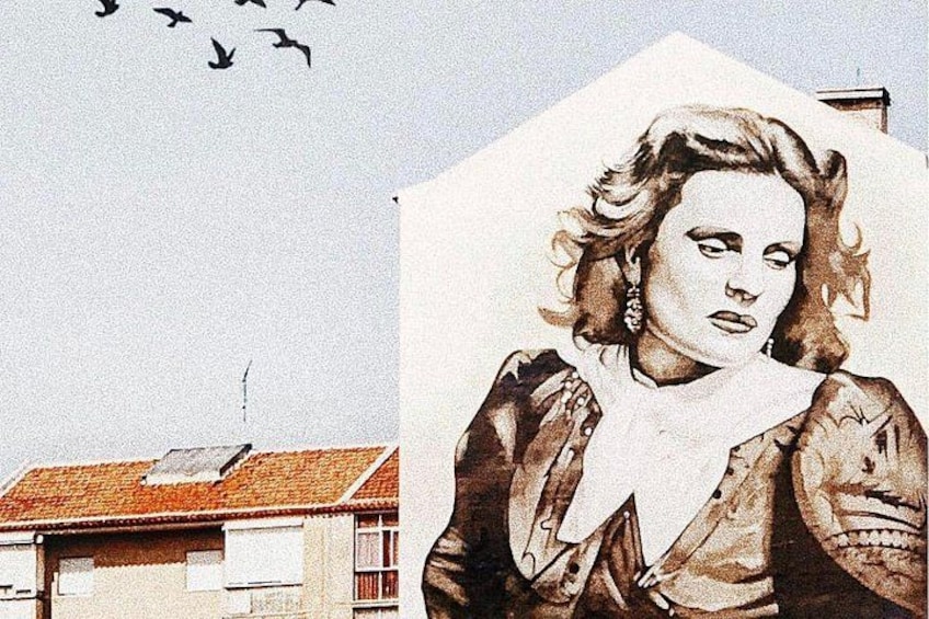 A building with a red-tiled roof and a mural of a person. 5