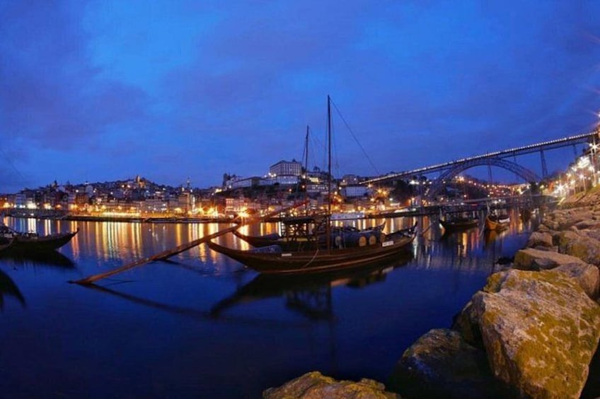 A nighttime cityscape with a bridge, boats, and illuminated buildings. 1