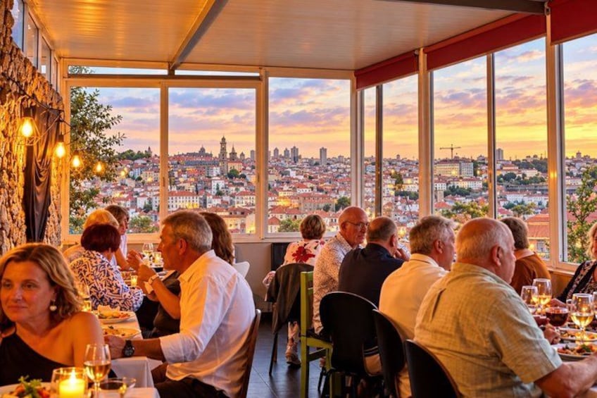 Een restaurant met gasten aan tafel, grote ramen met uitzicht op een stadsgezicht. 4