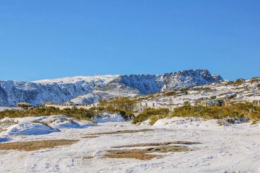 A snowy mountainous landscape with sparse vegetation and a clear blue sky. 3