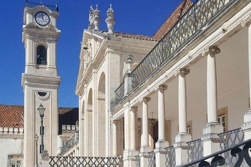 Un edificio histórico con una torre de reloj, columnas y un balcón. 5
