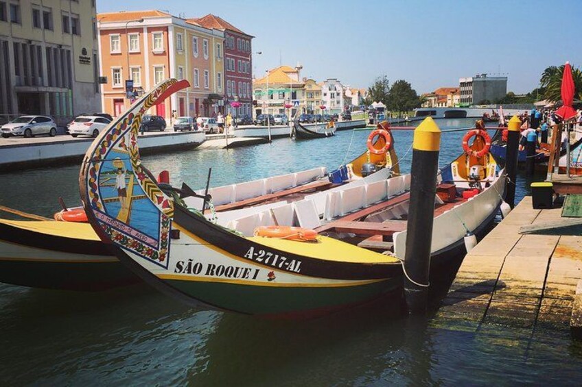 Un bote colorido amarrado en un muelle con un paisaje urbano al fondo. 1