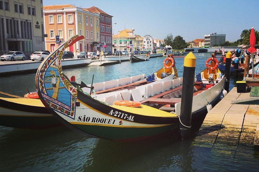 Un bote colorido amarrado en un muelle, con un paisaje urbano al fondo. 1
