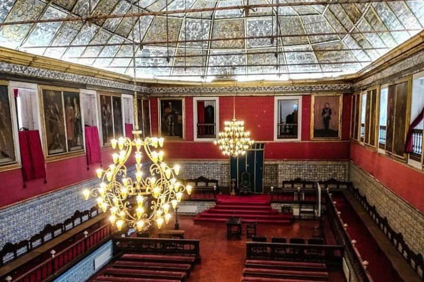 Un salón imponente con candelabros ornamentados, paredes rojas y techo de cristal. 2