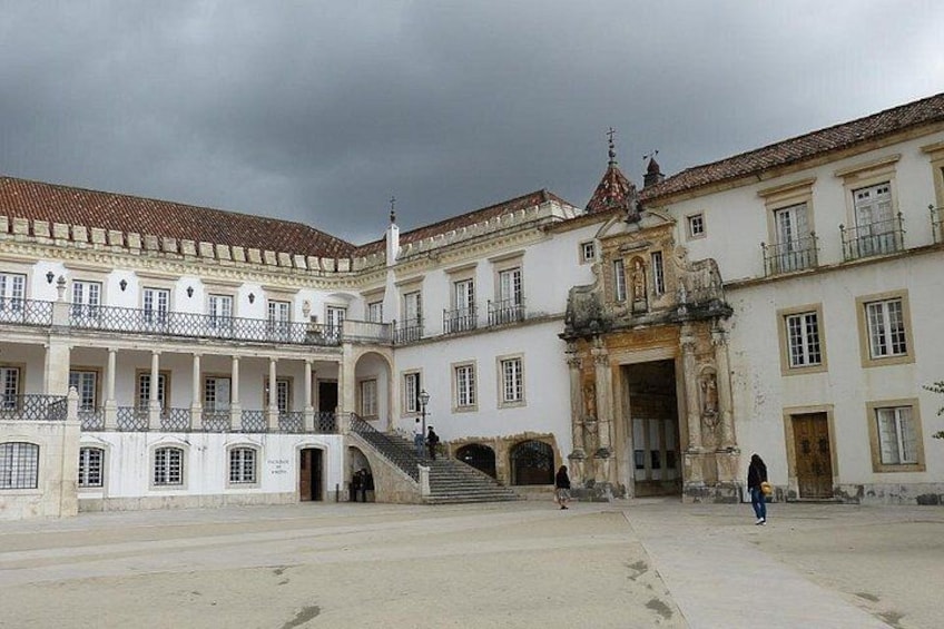 Un edificio histórico con un patio, una escalera y una persona caminando. 4