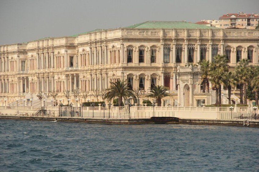 A large, ornate building with a green roof, palm trees, and a waterfront. 3