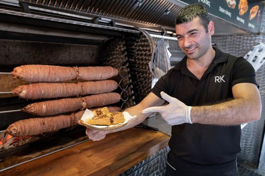 Una persona con una camiseta negra con un logotipo, sosteniendo una bandeja con un plato y una patata dulce grande. 2