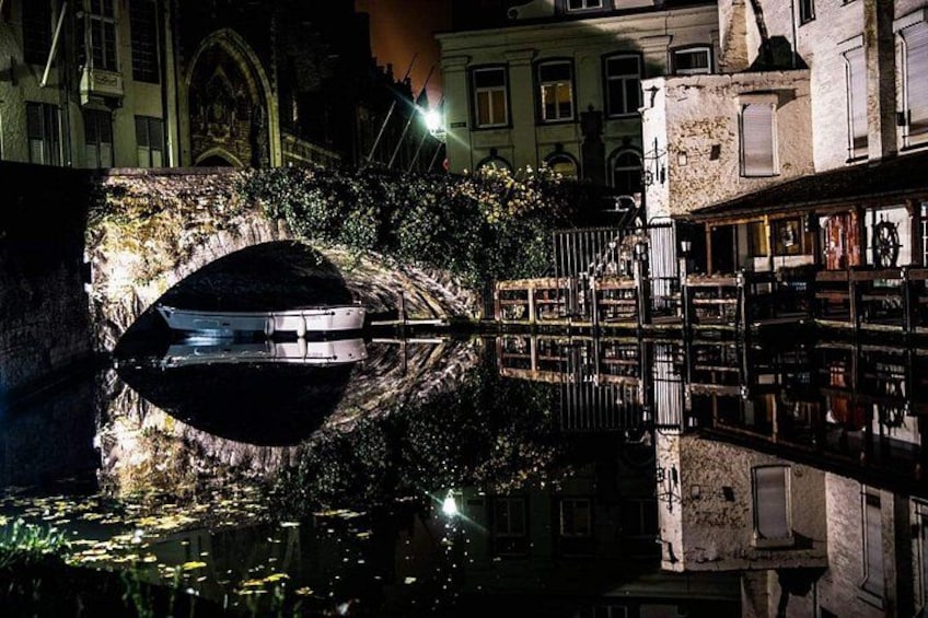 Un bote amarrado en un canal, rodeado de edificios y un puente. 5