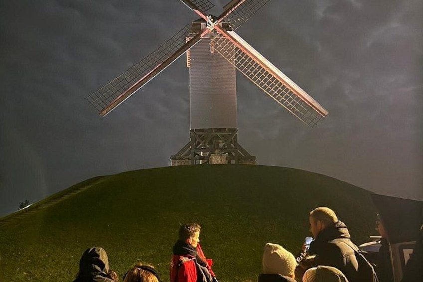 Un molino de viento en una colina, con gente al frente. 2