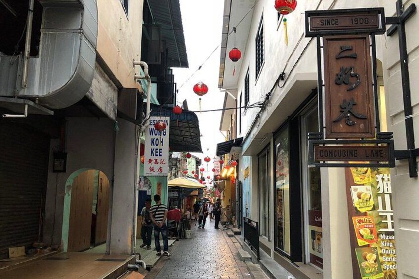 Une rue étroite bordée de boutiques, illuminée de lanternes rouges et ponctuée d’enseignes écrites dans une langue étrangère. 2