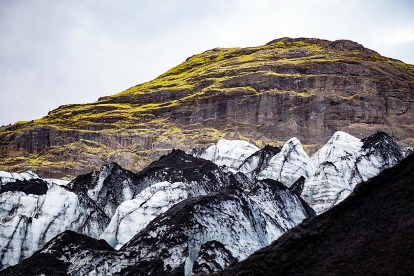 Une chaîne de montagnes aux sommets enneigés et une colline remarquable, couverte d’une végétation aux teintes jaunâtres. 4