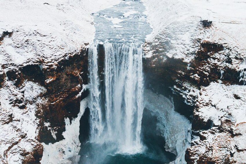 Une cascade se déversant sur une falaise rocheuse, le tout étant entouré de neige. 3