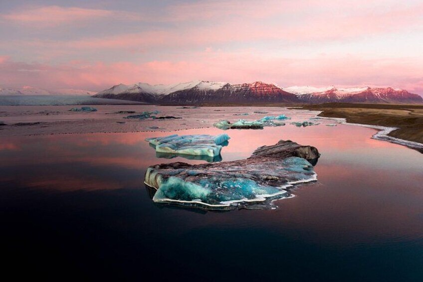 Icebergs flotando en aguas tranquilas con montañas al fondo. 3