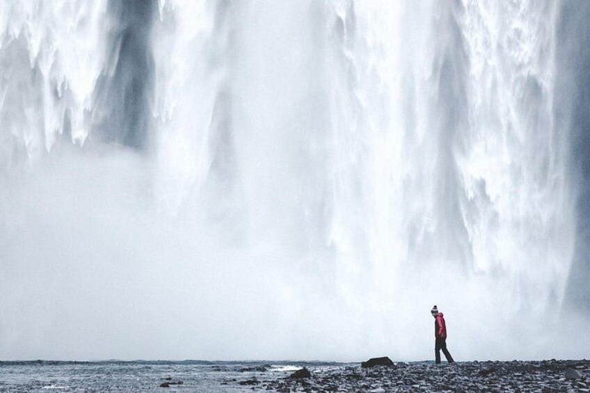 Una persona de pie frente a una cascada grande. 5