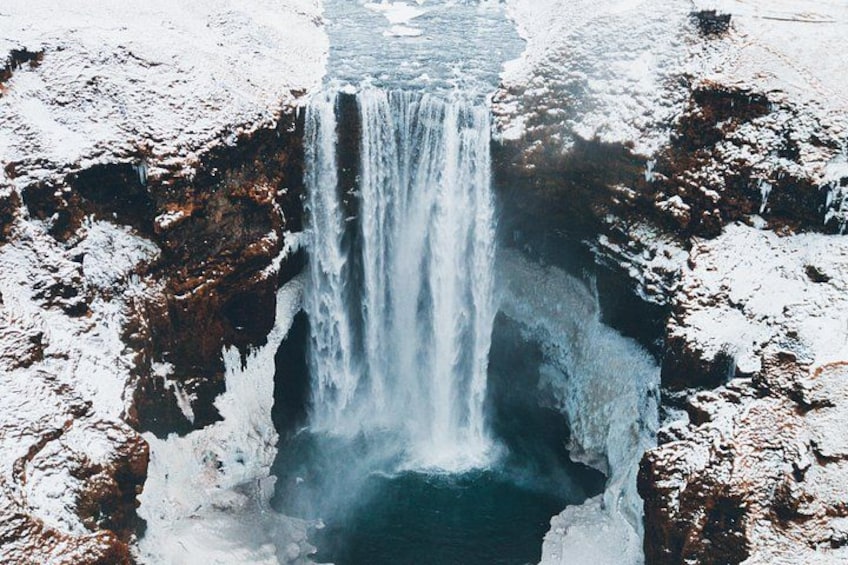 Una cascada se precipita sobre un acantilado rocoso rodeado de nieve. 2