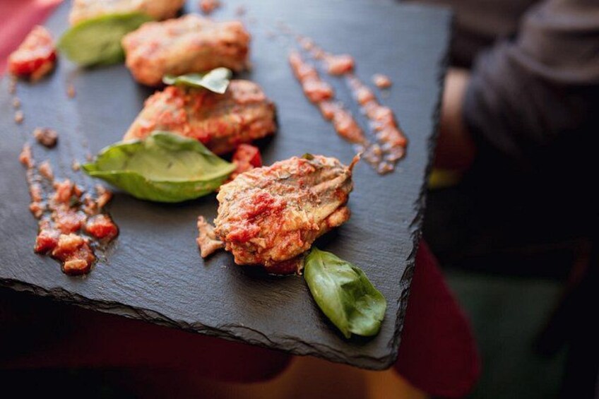 Un piatto con salsa al pomodoro e foglie di basilico su un vassoio in ardesia. 2
