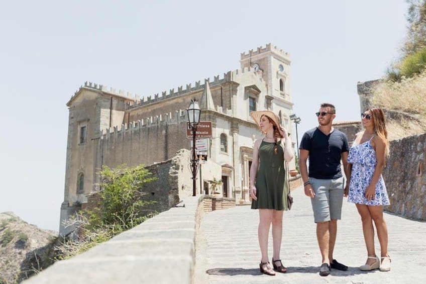 A historic building with a tower, a paved pathway, and a stone wall. 1