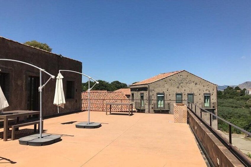 A rooftop terrace with a building, a railing, and a clear sky. 4