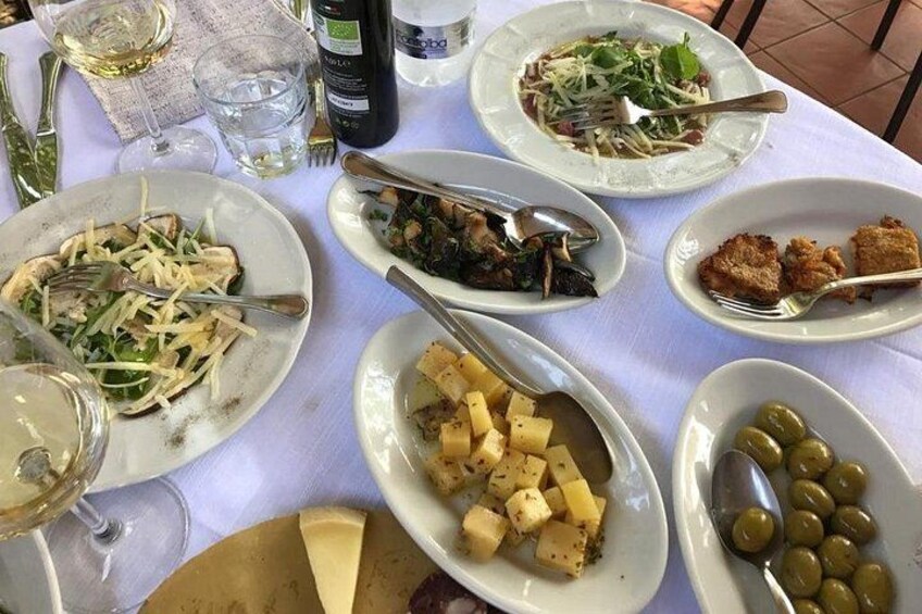 A table with various dishes, including pasta, a salad, and olives. 3