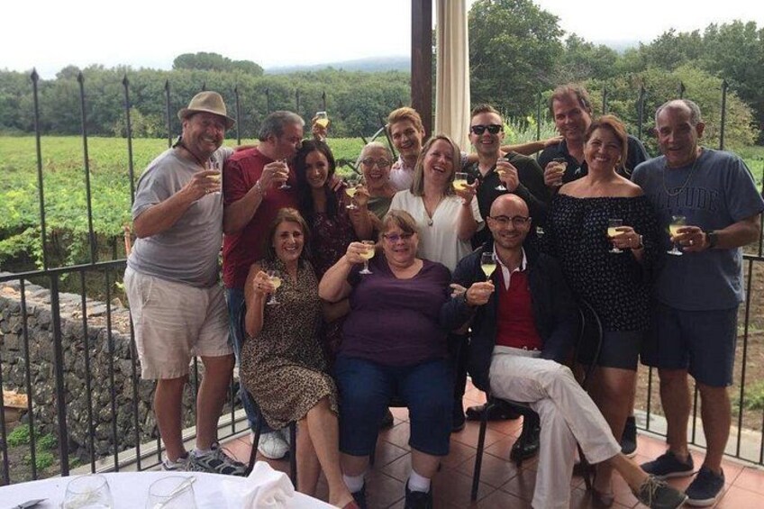 A group of people on a terrace with a vineyard in the background. 2