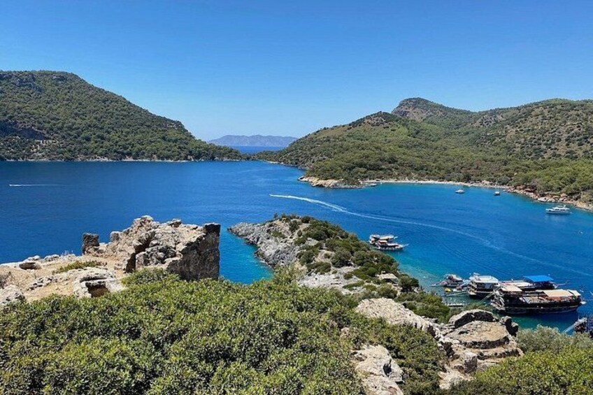 Un paisaje costero con aguas azules cristalinas, afloramientos rocosos y barcos anclados cerca de la orilla. 2