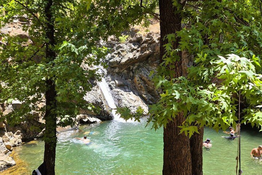 A waterfall, clear water, and people swimming. 4