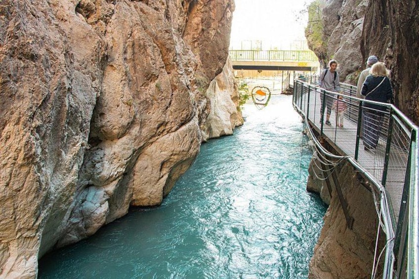A river canyon with a bridge, rocky cliffs, and a pedestrian walkway. 4